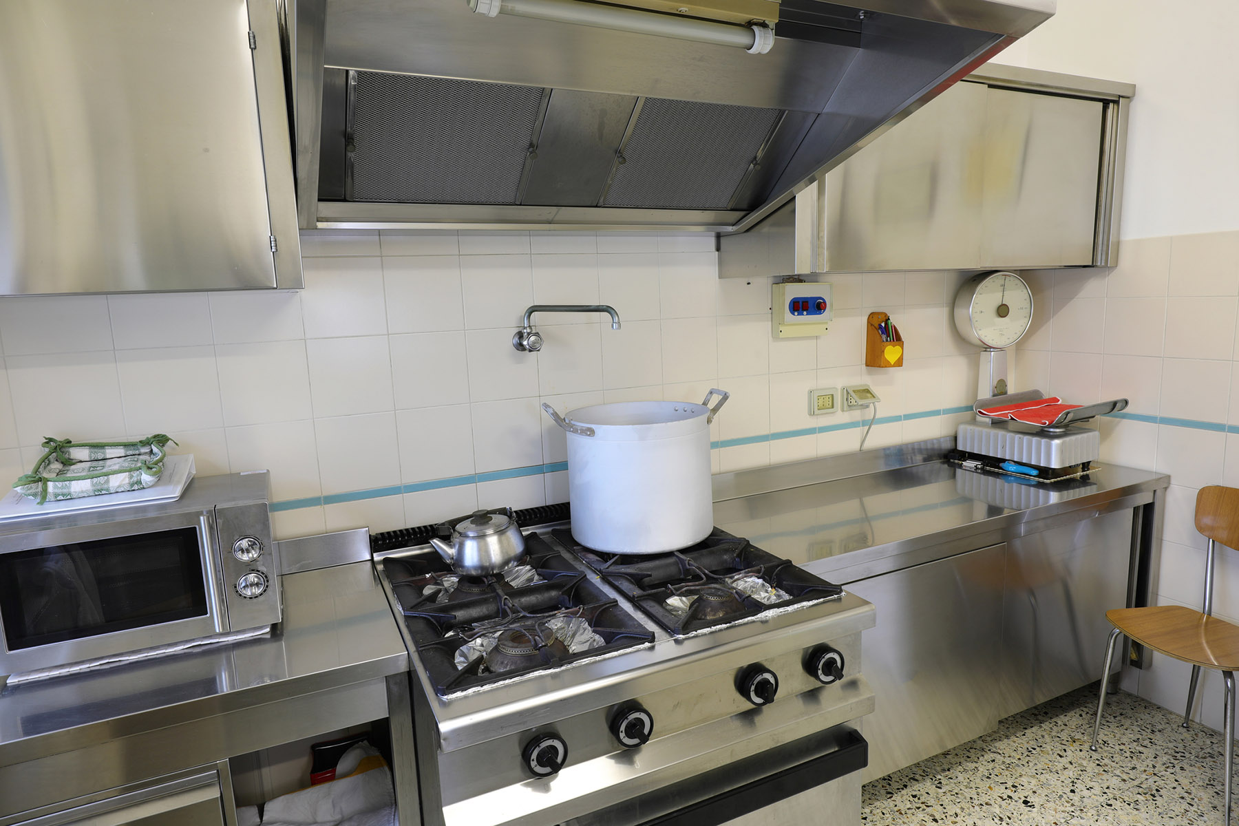kitchen with cooker hood and the stove with a huge pot
